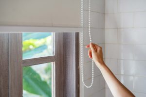 hand closing blinds during heatwave