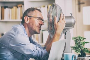 man in front of fan in office during heatwave