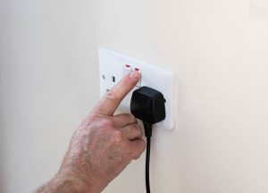 man switching off plug at socket