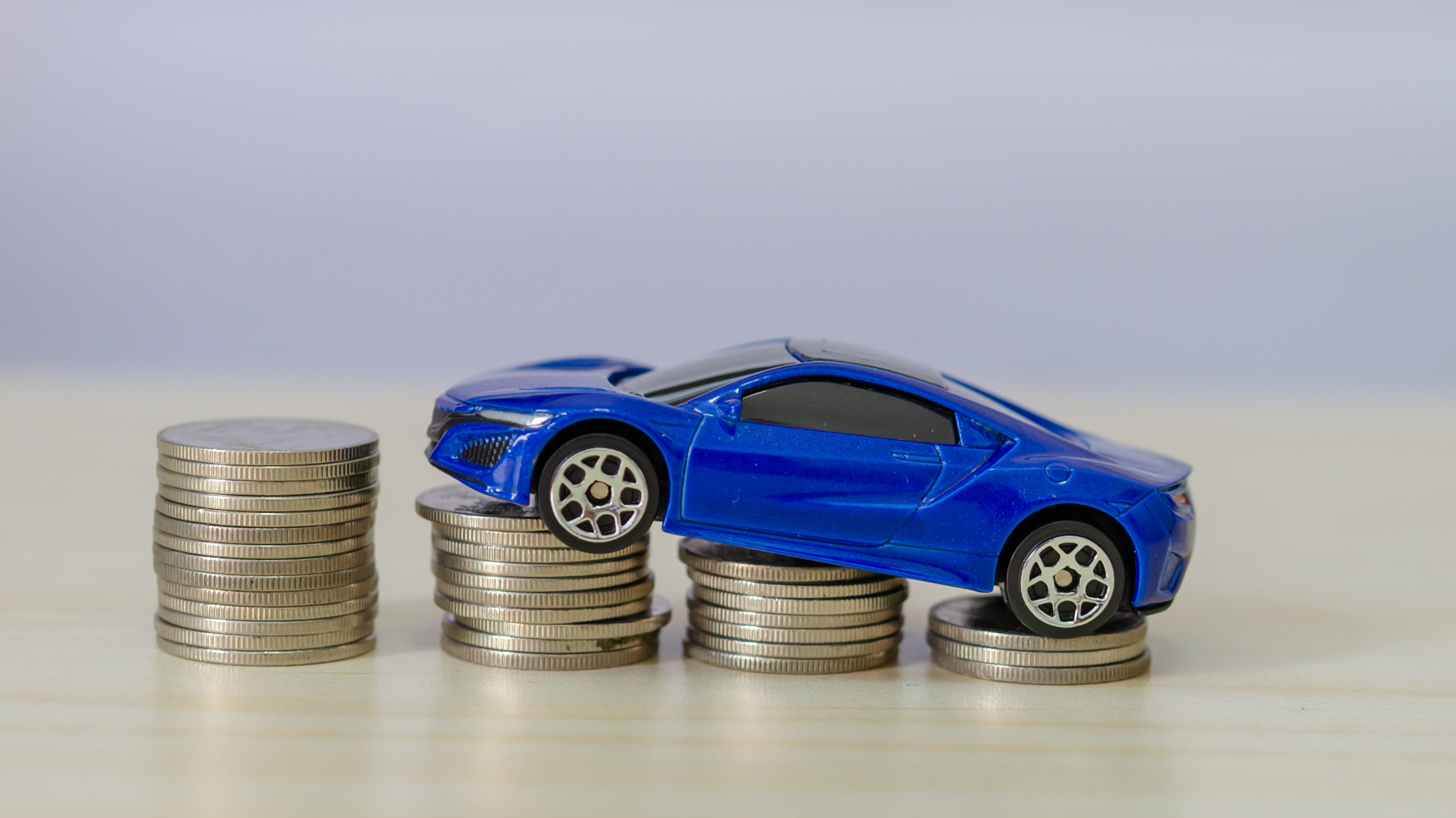 Toy blue car sitting on four stacks of 10p coins.