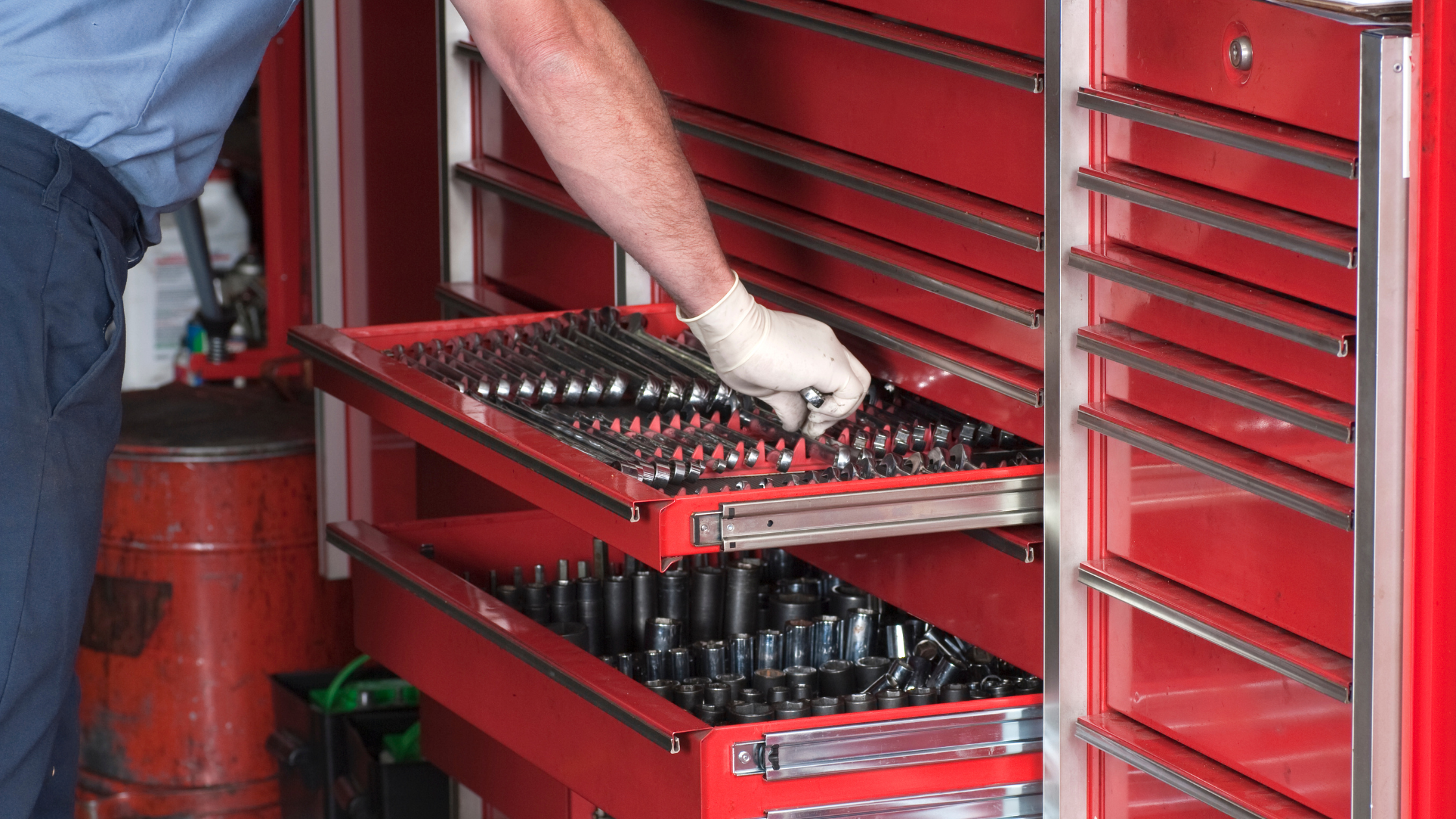 Image of a mans hand reaching into a red mechanics toolbox.