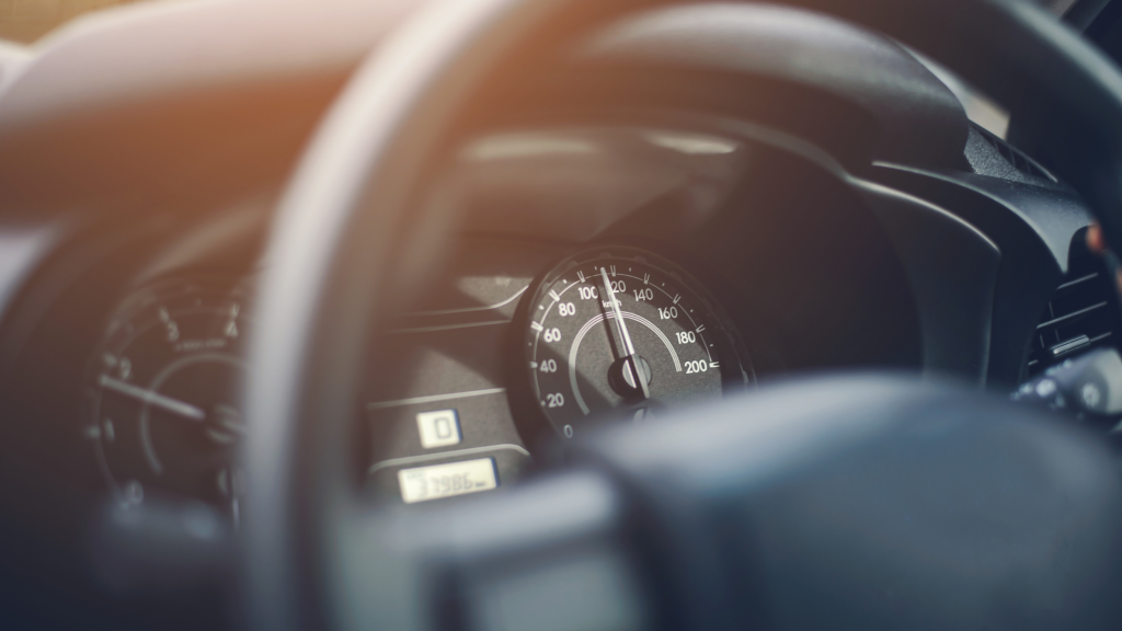 Image of steering wheel, focusing on the speedometer and mileage.