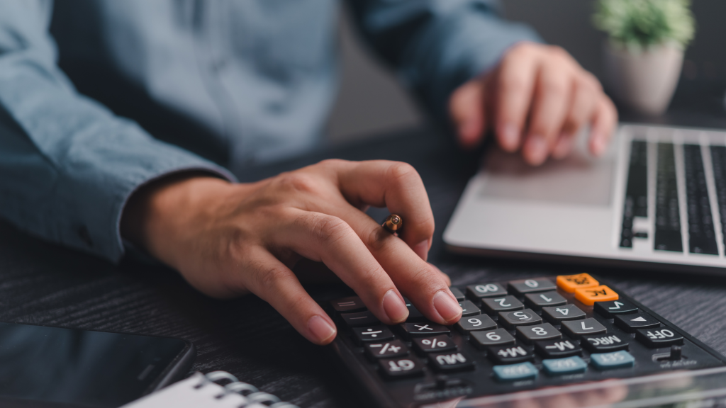 Man calculating mileage rates on a calculator at his desk.