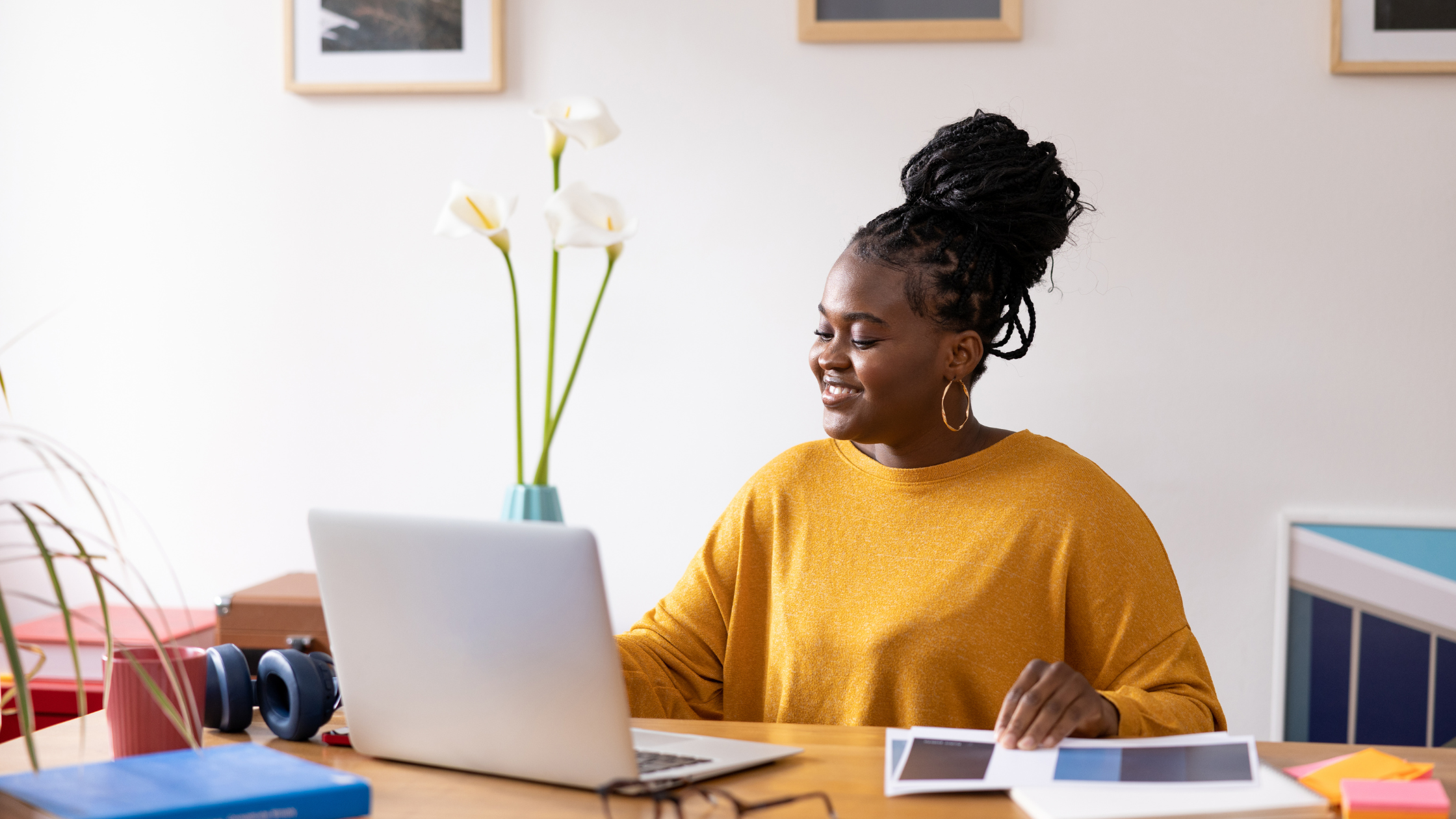 A woman sat at her desk at home, looking at her laptop screen.