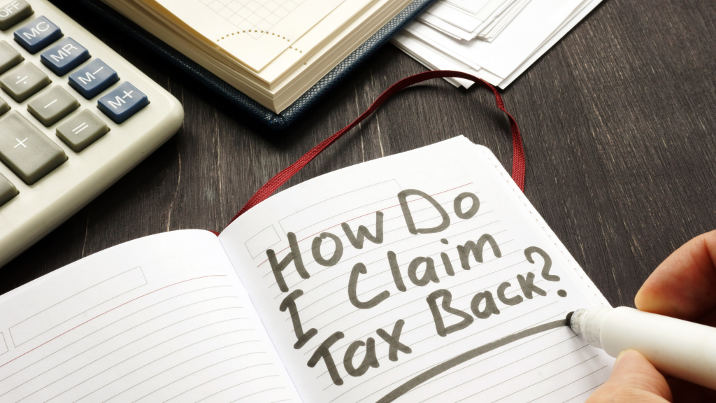 Notebook on a desk with writing on it reading 'how do i claim tax back'.