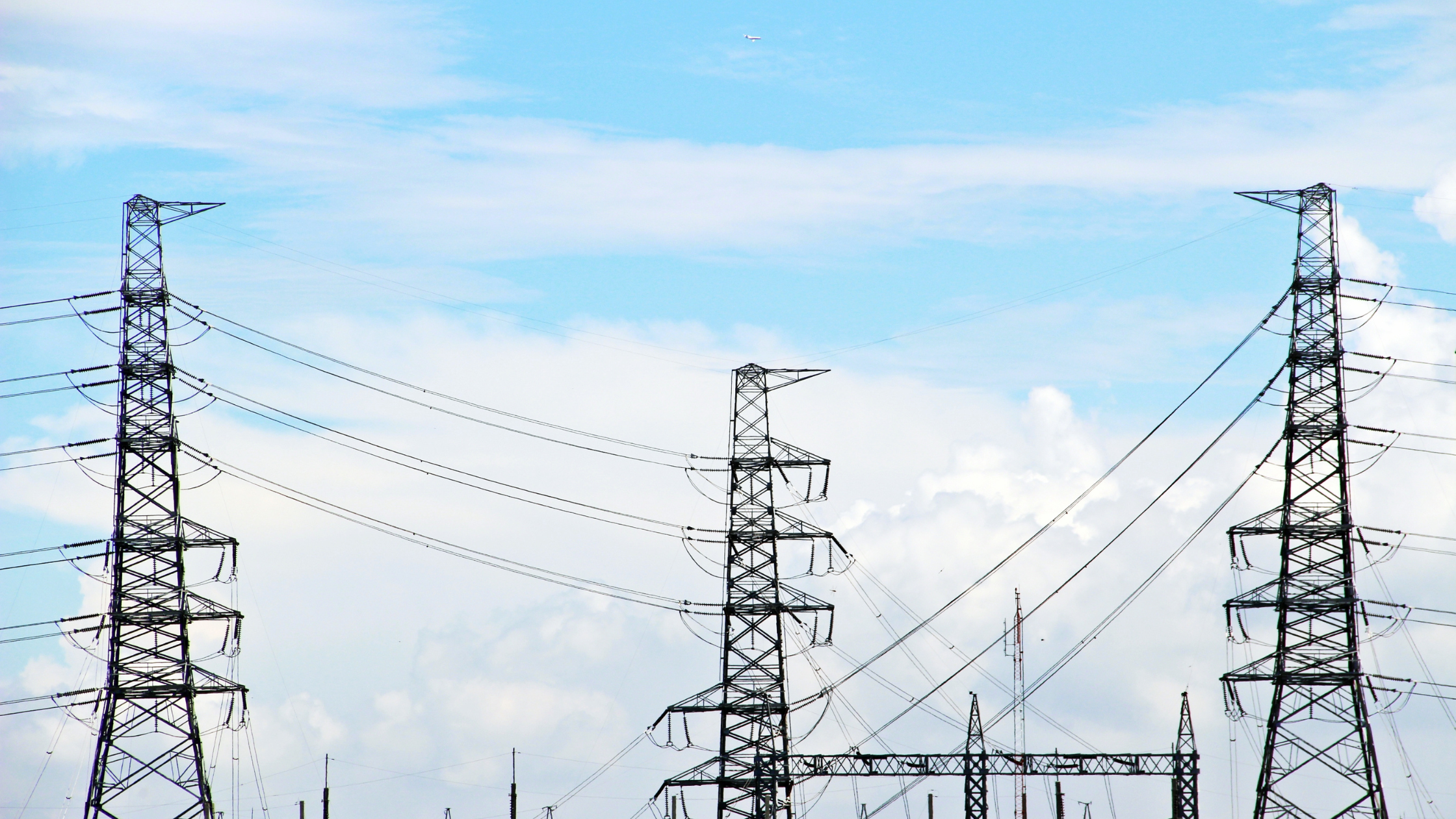 Three telecoms towers in a row, with a blue clouded sky in the background.